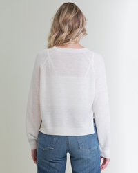 Woman facing away from the camera, wearing a Margaret O'Leary Rib Linen PO in White and blue jeans, standing against a plain background.