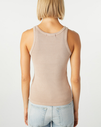 Woman wearing an AMO beige Long Rib Tank in Taupe made in Los Angeles and blue jeans, viewed from the back.