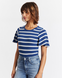 Woman wearing a blue and white nautical printed AMO Sylvie Tee in Natural/Navy with high rise denim blue jeans.