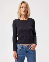 Woman wearing an AMO black L/S rib tee cropped top and blue high-waisted jeans.