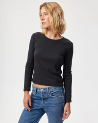 Woman posing in an AMO L/S Rib Tee in Black and high-waisted blue jeans.
