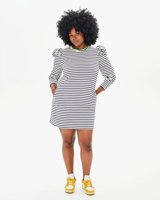 Woman in a Clare V. Le Puff Dress in Navy & Cream Stripe with puff shoulders and yellow sneakers posing with hands on hips against a white background.