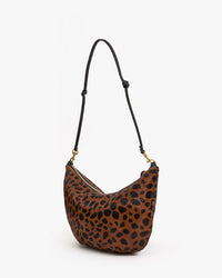 The Clare V. Lune - Tan Leopard bag features a brown and black leopard print hair-on leather, a black adjustable strap, and gold hardware, shown against a plain white background.