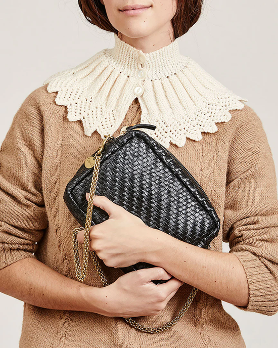 Woman holding a Clare V. Black Woven Zig-Zag Midi Sac with a gold chain strap.