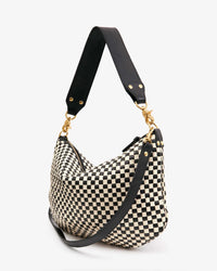 The Clare V. Woven Checker Moyen Messenger in Black & Cream features black leather straps and gold hardware, handmade in Bangladesh, and is displayed against a plain white background.
