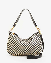 The Clare V. Woven Checker Moyen Messenger in Black & Cream is a medium-sized leather bag with a black and cream checkered design, gold hardware, short black top handle, detachable strap, and is handmade in Bangladesh.