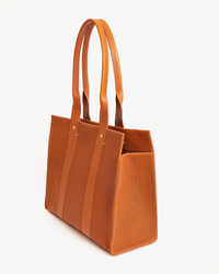 Noemie in Cuoio Perf brown tote bag by Clare V. against a white background.