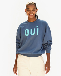 Woman smiling in an oversized Clare V "Oui Oversized Sweatshirt in Faded Navy w/ Light Blue".