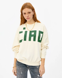 Woman wearing an oversized Clare V Grand Block Ciao Oversized Sweatshirt in Cream / Evergreen paired with blue jeans.
