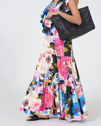 Woman in a floral dress holding a Dragon Diffusion Cannage Max in Black handwoven leather tote.