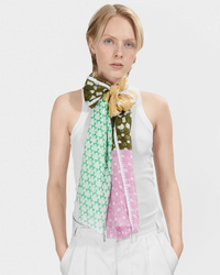 Woman wearing a white sleeveless top with an Épice Dot Panel Scarf in Green tied around her neck.