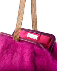 Close-up of a vibrant pink, furry handbag with a gold chain handle and a Marian Paquette Susan Solid Mohair Clutch in Fuchsia brand label inside.