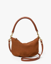 The Clare V. Petit Moyen Messenger in smooth hazelnut nubuck features a rounded shape, short handle, detachable and adjustable crossbody strap with gold hardware, shown against a plain white background.