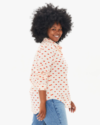 Woman with curly hair smiling, wearing a Clare V. Phoebe Blouse in Blush w/ Poppy Allover Lips and jeans.