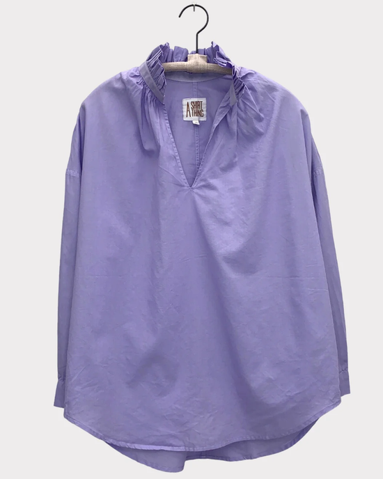 A Penelope - Cabo in Lilac long-sleeve pop over shirt hanging on a wooden hanger against a white background by A Shirt Thing.
