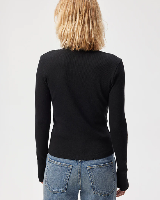 Woman wearing a slim fit, AMO Lacy Rib Cardigan in Black and blue denim jeans viewed from behind.