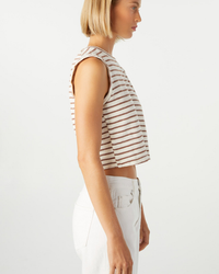 Side profile of a woman wearing a striped Sleeveless Babe Tee in Bone and AMO denim cropped fit pants.