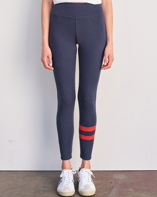 Woman standing against a plain background wearing Sundry's Navy Striped Leggings with an elastic waistband and sneakers.