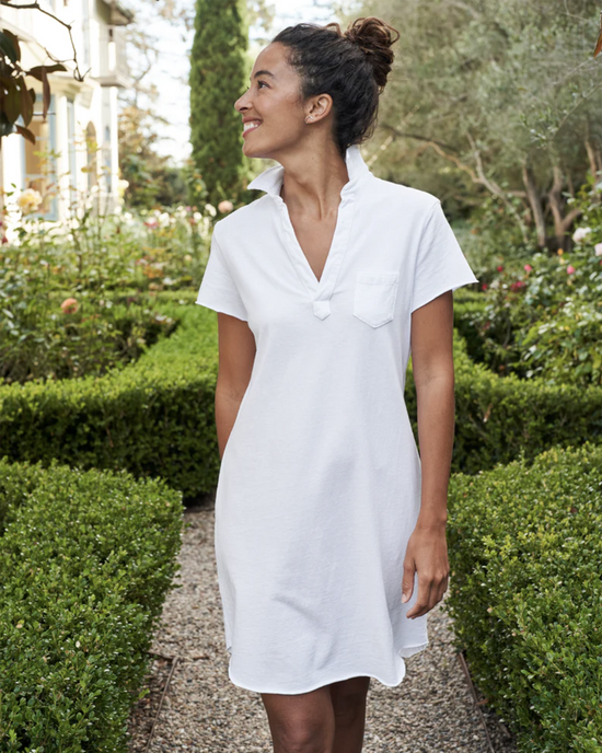 Woman in a Frank & Eileen Lauren S/S Polo Jersey Dress in White, short sleeve and made of 100% Cotton Heritage Jersey, smiling and looking to the side in a garden pathway.