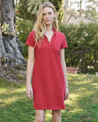 A woman standing in a garden area wearing a Frank & Eileen Lauren S/S Polo Jersey Dress in Double Decker Red.