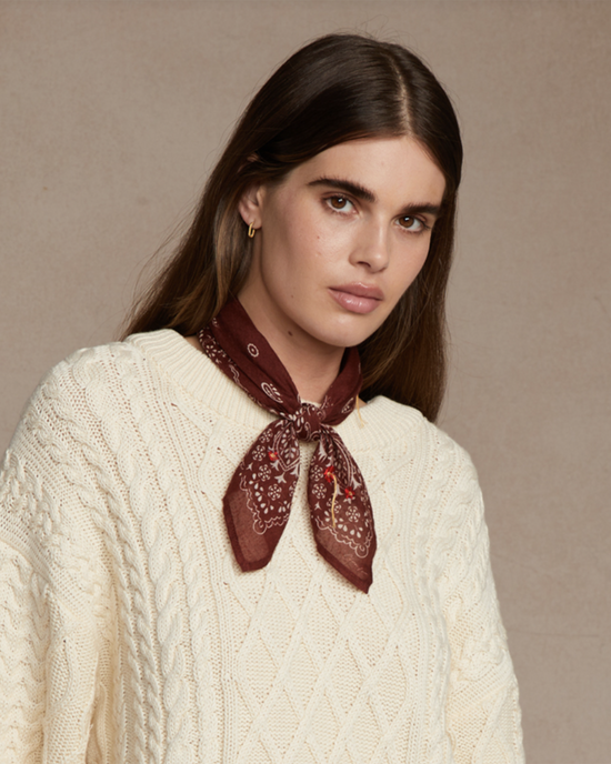 Woman wearing a cream cable knit sweater and a Floral Bandana in Fired Brick by Chan Luu.