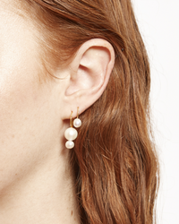 A close-up of a woman's ear wearing a Chan Luu CL 2 White Pearl Drop Earring, 18k gold plated sterling silver.