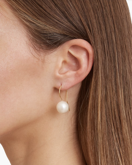 A close-up view of a woman wearing a Chan Luu CL White Pearl Drop Earring with 18k gold plated sterling silver.