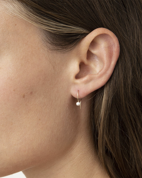 Close-up of a woman's ear wearing a Chan Luu 14K Drop Earrings in White Pearl with a small white freshwater pearl ornament.