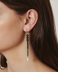 A woman wearing Chan Luu Gota Earrings in Emerald with a clear dangling gemstone.