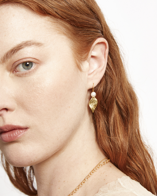 Woman showcasing a Chan Luu Falling Leaf Drop Earrings in White Pearl and a delicate chain necklace.