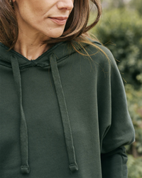 Woman in a Kane Capelet Hoodie in Evergreen by Frank & Eileen outdoors.