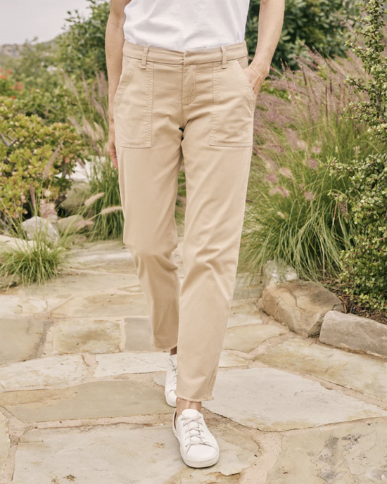 A person standing on a stone pathway wearing Frank & Eileen's Blackrock Ultility Pant in Khaki and white sneakers.