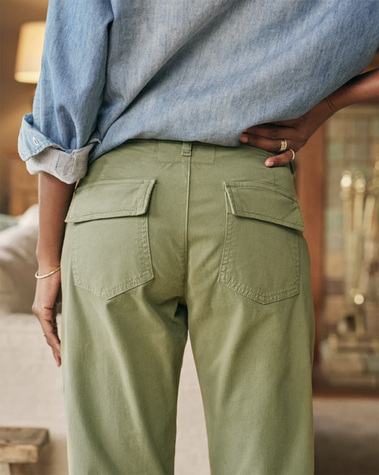 A person stands with their hand on their hip, wearing a chambray shirt and olive green Frank & Eileen Blackrock Utility Pant in Army with back pockets.