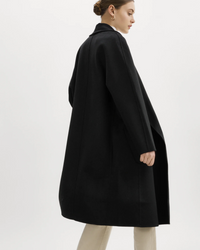 Woman in a Lamarque Thara Jacket in Black featuring double-faced wool and oversized fit, paired with light trousers seen from the side.