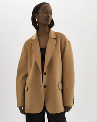 A woman modeling a Lamarque Ennis Jacket in Camel with a notched lapel.