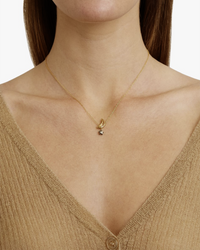 Woman wearing a Chan Luu Moon & Star Necklace in Citrine Mix with a citrine moon charm on an 18k gold plated sterling silver chain and a tan v-neck top.