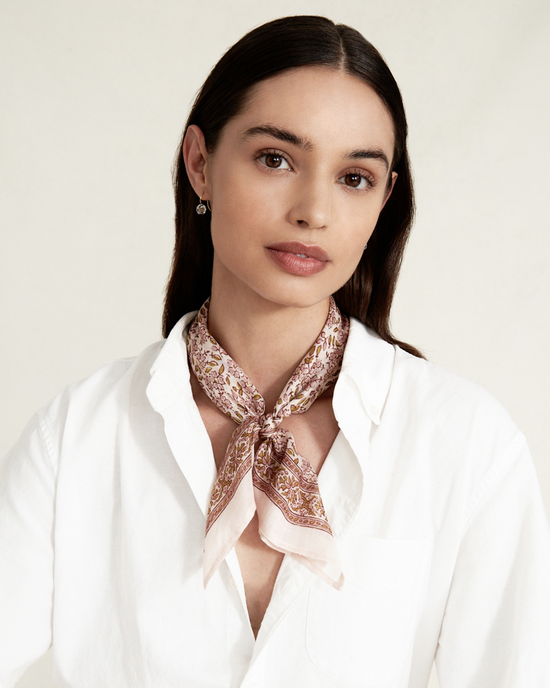 A woman with a white shirt and a Chan Luu Vintage Floral Bandana in Mauve Chalk neck scarf.