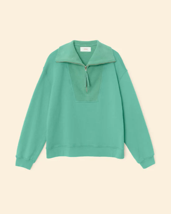 The XiRENA Kat Sweatshirt in Field Green is a relaxed-fit, 100% cotton long-sleeve pullover with a half-zip collar, shown on a beige background.