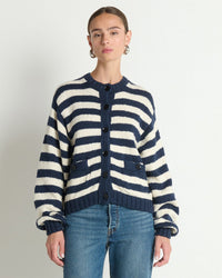 A person wears the Nation LTD Tessa Cardigan in Marine Stripe—an oversized navy and white striped cotton cardigan—with blue jeans, standing against a plain white background.