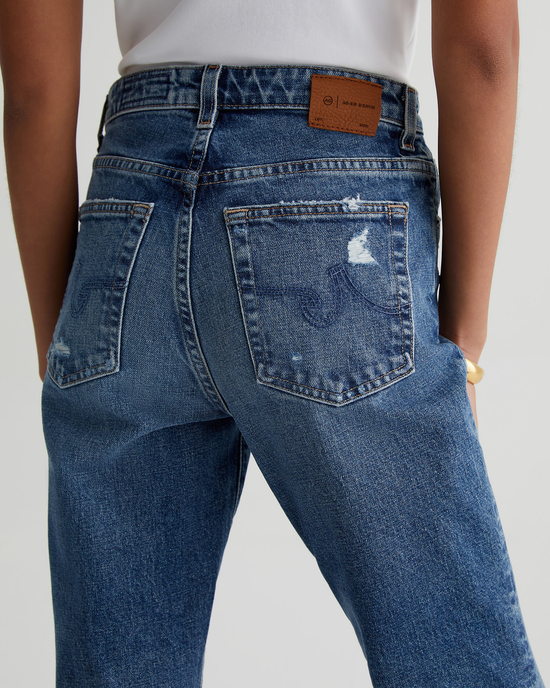 Close-up of a person wearing AG Jeans, focusing on the back pocket with a visible Kinsley in 15Ys Upstate logo patch.