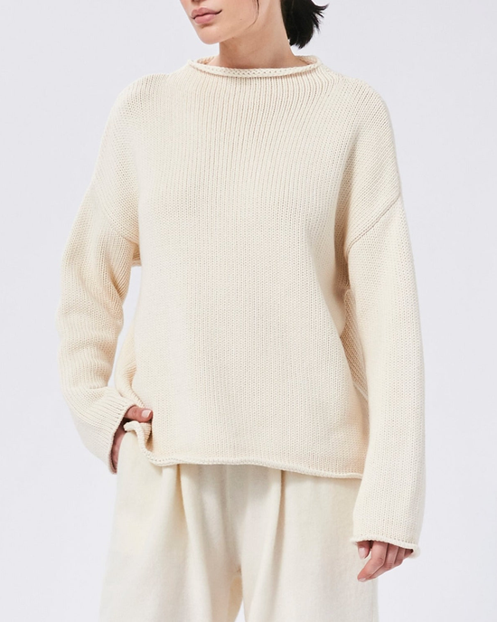 A person wearing a Demylee Lamis Boatneck Sweater in Off White and light pants.