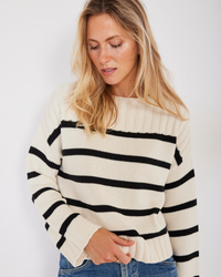 A woman in a Madison Stripe Pullover in Ivory Stripe sweater by Not Monday looking down to her right.