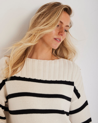 Woman with blond hair wearing a Not Monday Madison Stripe Pullover in Ivory Stripe, looking to the side against a white background.