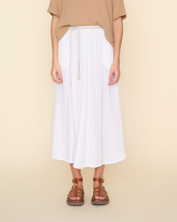 Woman standing in a XiRENA Deon Skirt in White and brown sandals against a neutral background.