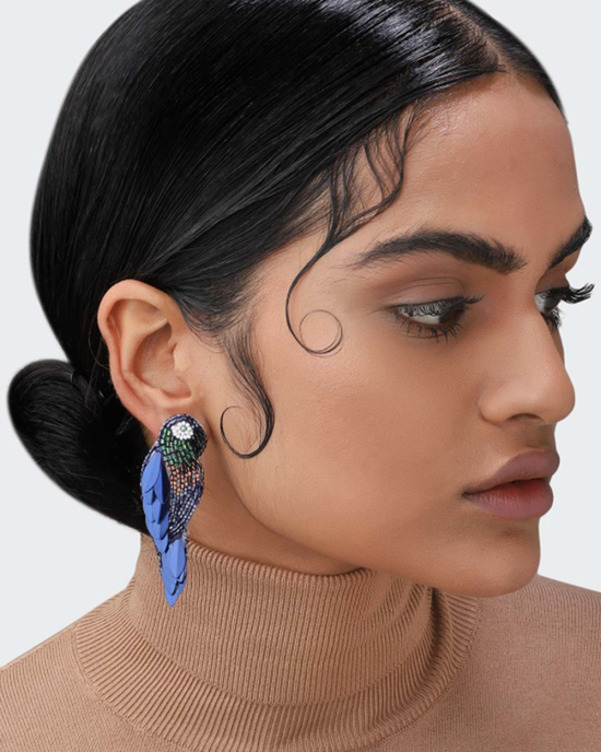 Profile of a woman wearing a turtleneck and a large, colorful Olivia Dar Ara Earrings in Navy with micro beads.