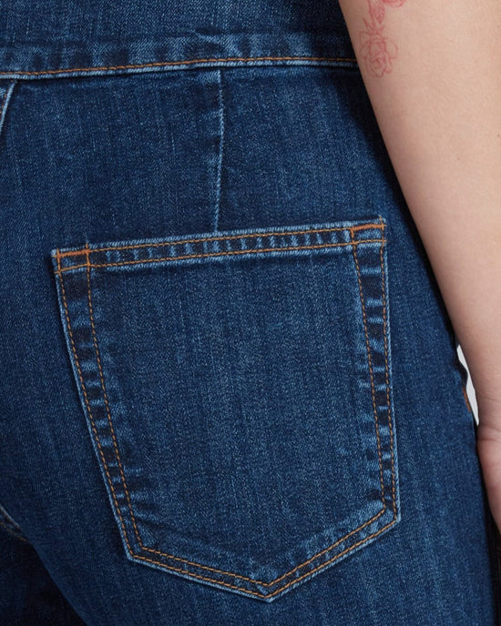 Close-up of the back pocket on ASKK NY's Brighton in Dark Stone, made from Japanese stretch denim with orange stitching. A tattooed arm is partially visible. Features a flattering high-rise wide leg fit.