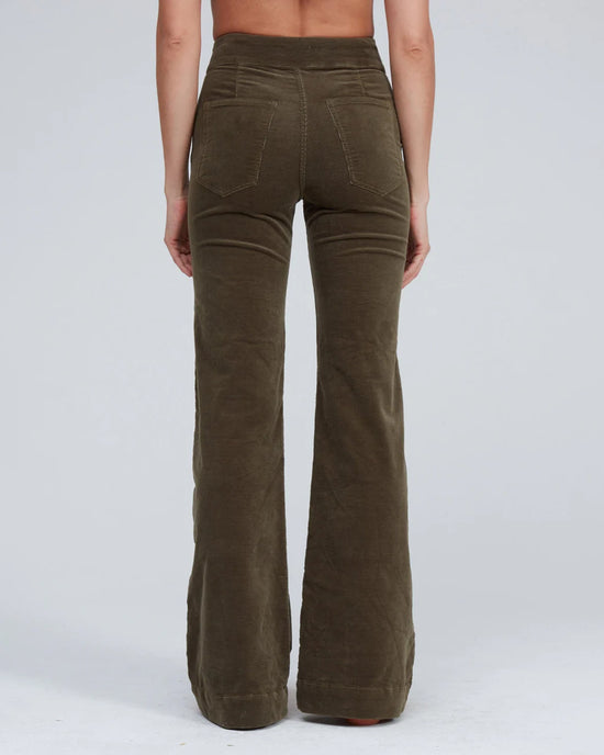 A person stands with their back to the camera, wearing ASKK NY Brighton Corduroy Wide Leg pants in Safari Green with back pockets, set against a plain light gray background.