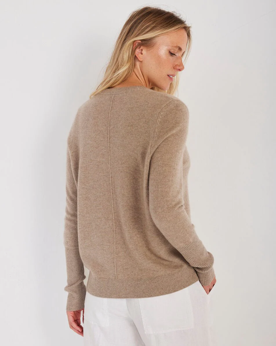 A woman seen from behind wearing a Not Monday Ava Cashmere V Neck in Latte sweater with white pants against a white background.