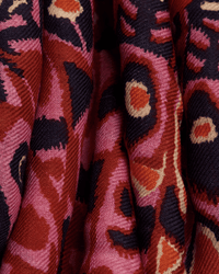 Close-up of the Inoui Editions Square / Carre 130 Papillons in Red, featuring bold abstract patterns in red, pink, black, and cream. Swirling shapes and soft folds evoke the vibrant look of an oversized bandana scarf.