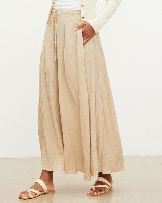 A person wearing a Bailey Skirt in Biscuit with a drawstring elastic waist, paired with a white top and gold sandals by Velvet Graham & Spencer.